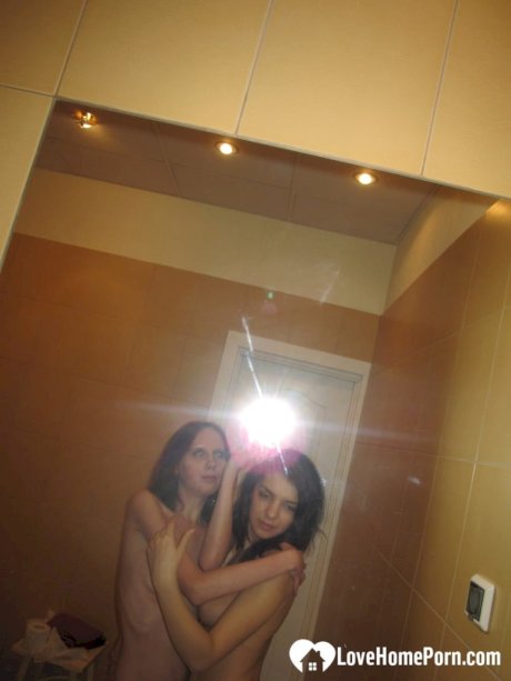 Amateur lesbians fondle each other's small tits while posing in the mirror