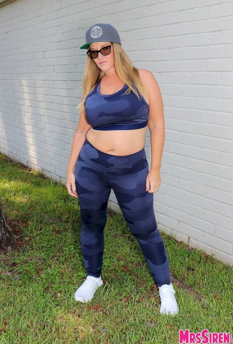 Short cougar Dee Siren posing in her sexy leggings and top in the garden
