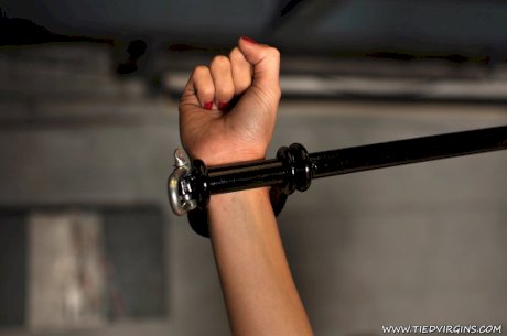 Topless blonde sports a ball gag while restrained to spreader bars