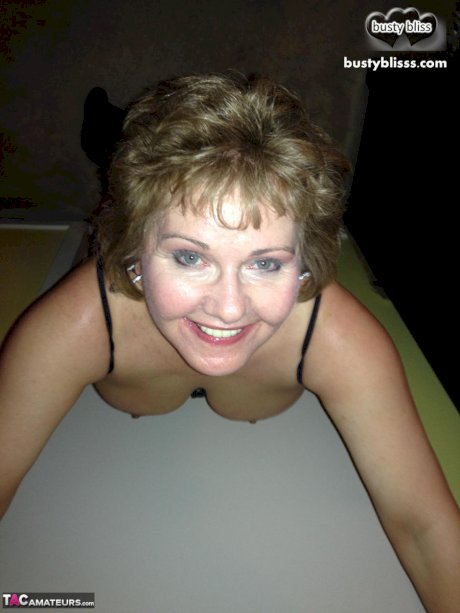 Mature woman Busty Bliss uncups her natural tits while wearing a black thong