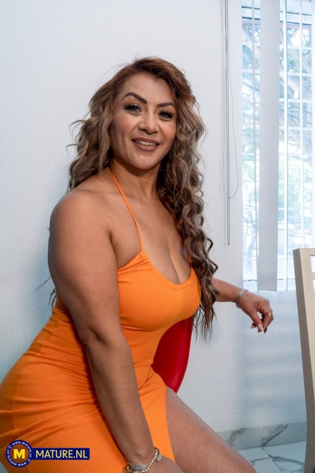 Mature Latina woman undresses for a nude solo shoot on a red chair - Photo 3