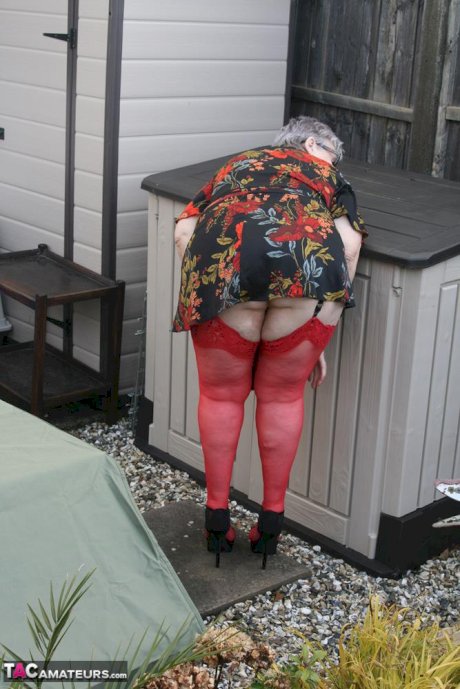 Naughty granny shows her tits and twat in backyard wearing red stockings