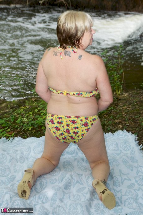 Thick mature woman Speedybee strips naked on a blanket down by the river