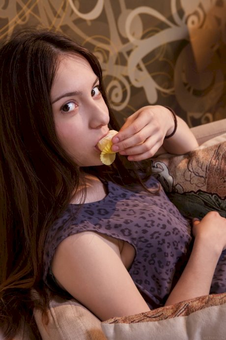 Young brunette with long hair strips naked on a sofa in a tempting manner porn pics