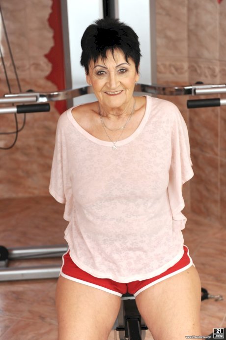 Sassy granny Anastasia strips at the gym to spread naked on the equipment