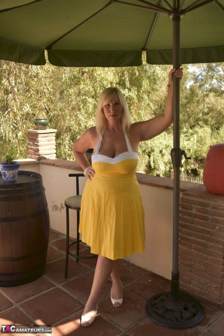 Overweight blonde Melody works free of a pretty dress while on a balcony
