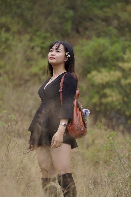 Gorgeous Asian babe posing in her black dress and boots in nature