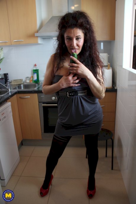 Spanish housewife with big hair masturbates with a cucumber in her kitchen