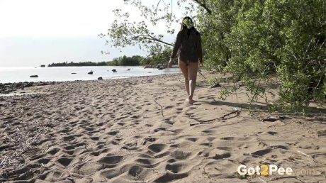 Dark-haired girl Anarid lies back on a sandy beach while taking a piss