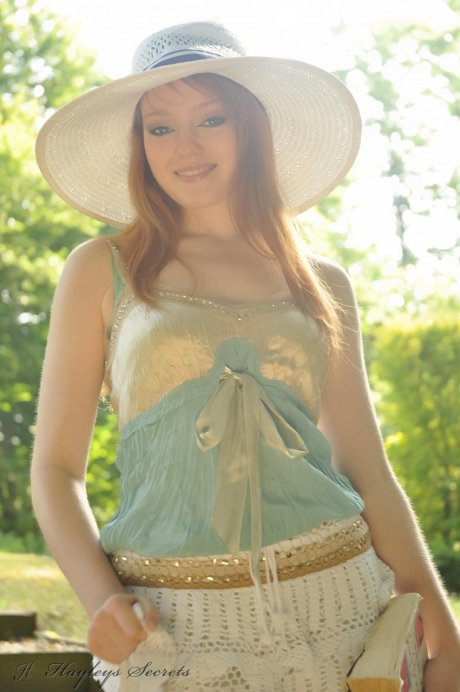 Natural redhead Charlie Edwards removes a sunhat while getting naked in a yard