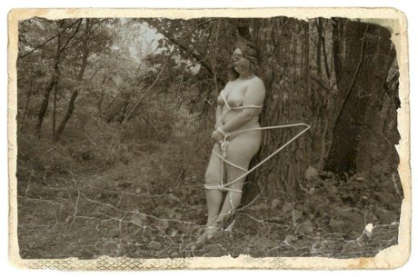 Overweight female is tied to a tree in the woods while naked and blindfolded