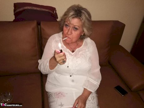Mature lady exposes her large tits while having a smoke in pantyhose