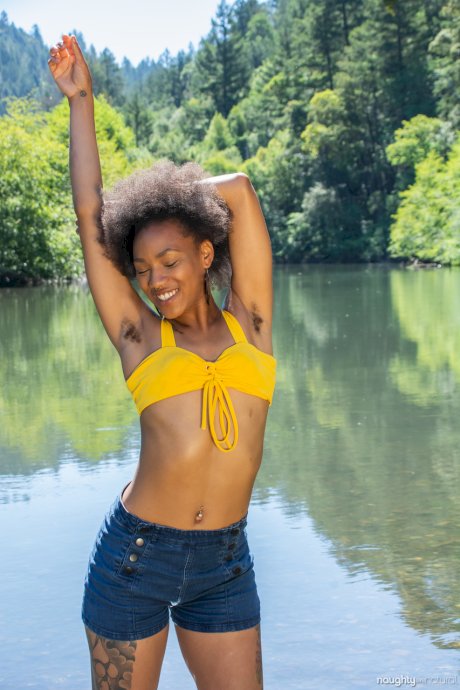 Afro-American babe Nikki Darling exposes her hairy inked body in the river