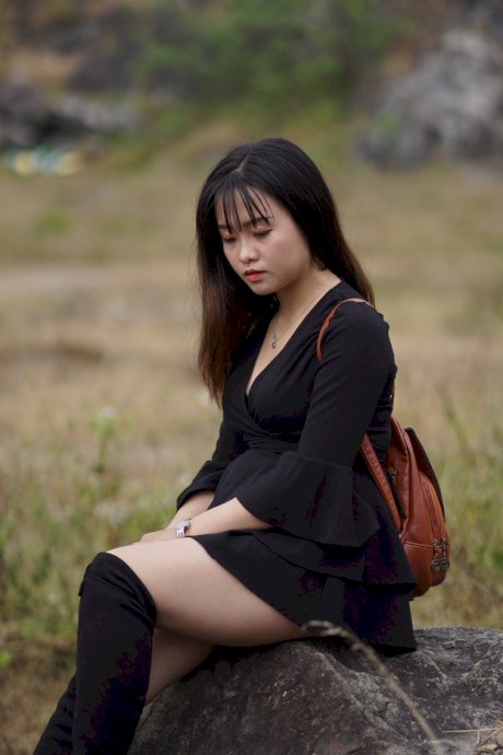 Gorgeous Asian babe posing in her black dress and boots in nature