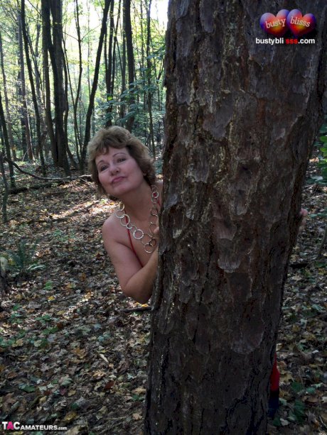 Older lady Busty Bliss gets completely naked while in a forest