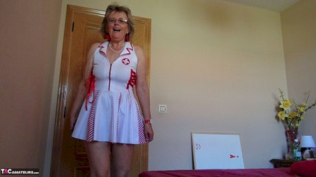 Old lady Abby Roberts frees sagging tits from nurse outfit before dildo riding