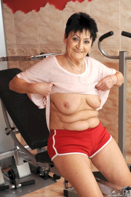 Sassy granny Anastasia strips at the gym to spread naked on the equipment