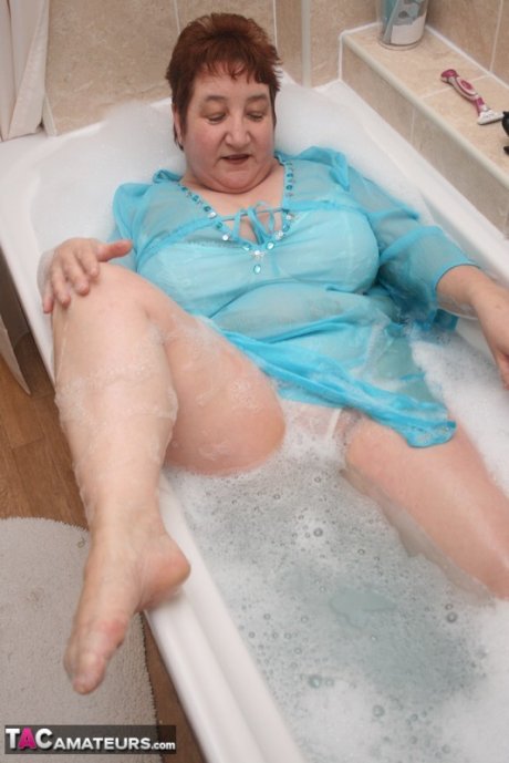 Redhead nan Kinky Carol parks her fat figure in a tub while fully clothed
