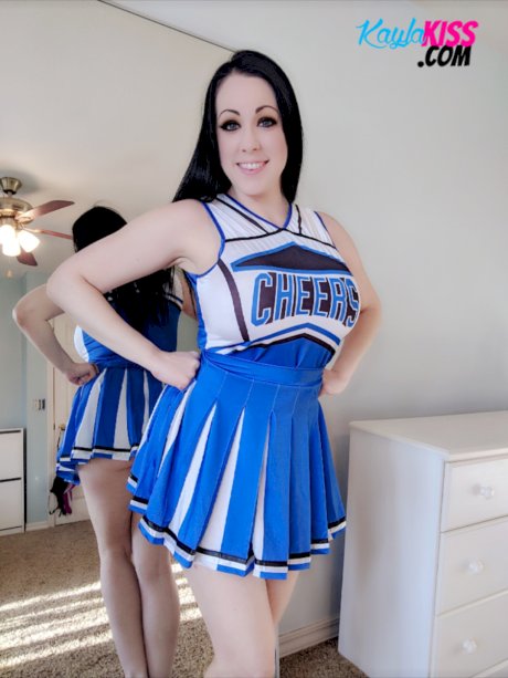 Dark-haired cheerleader Kayla Kiss uncovers her big natural tits in OTK socks