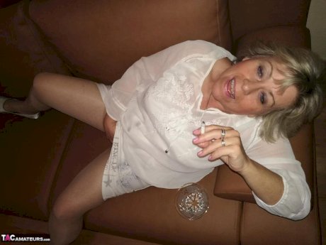 Mature lady exposes her large tits while having a smoke in pantyhose