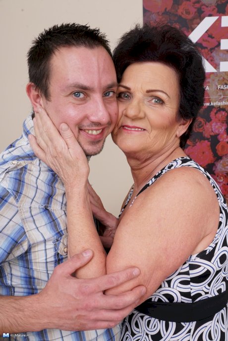 Old woman kisses her toy boy before the undress each other on sofa