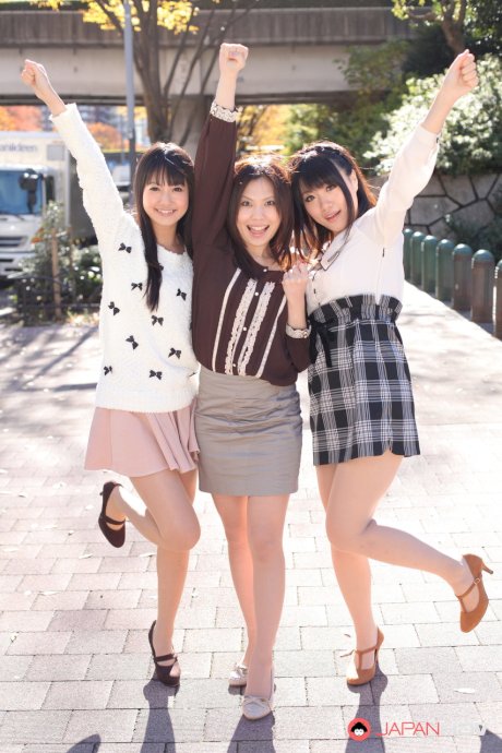 Three Japanese girls in skirts pose outdoors for a SFW shoot