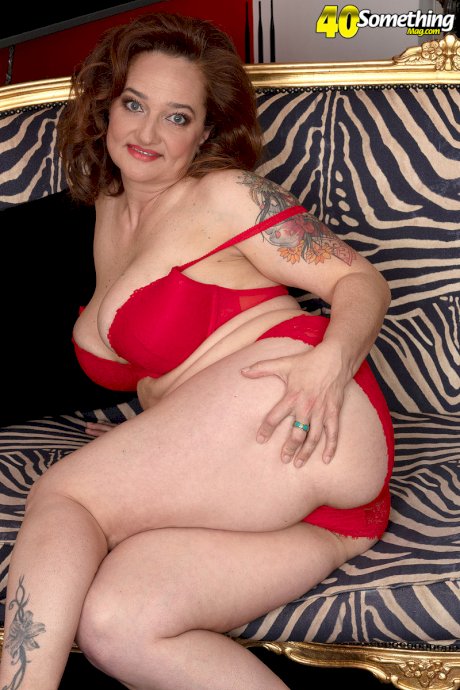 Mature redhead Amelie Azzure releases her curvy figure from a red dress