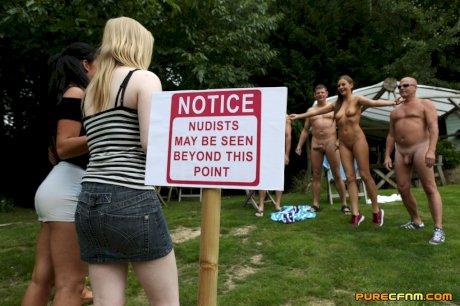 Lovely clothed female students blow off a nudist colony outdoors