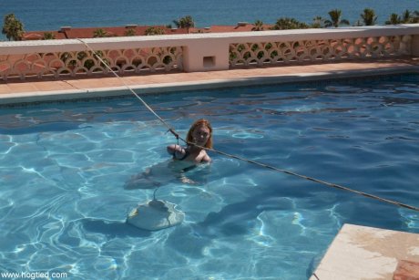 Thick redhead is hogtied in a swimming pool before being freed - Photo 1