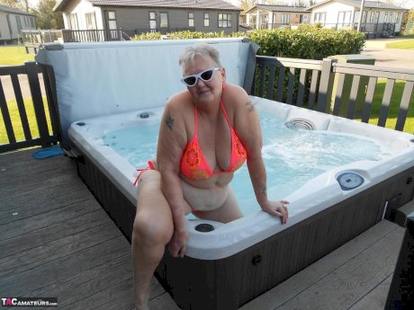 Fat nan bares her boobs while in a patio hot tub before getting naked on a bed