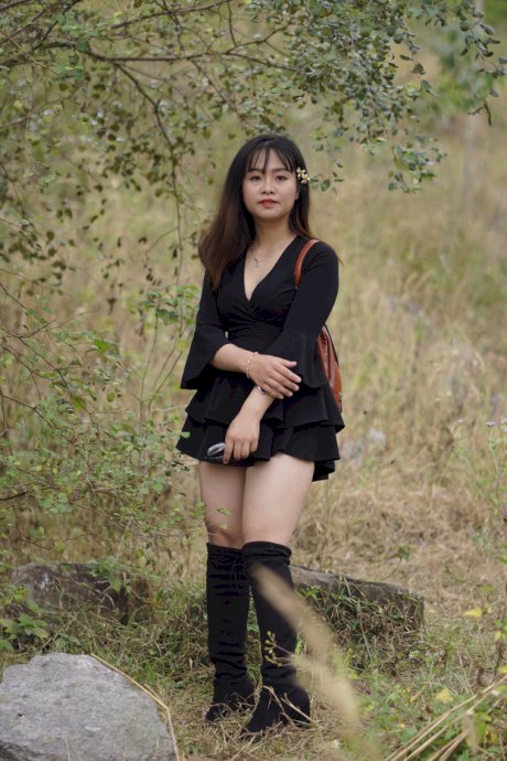 Gorgeous Asian babe posing in her black dress and boots in nature