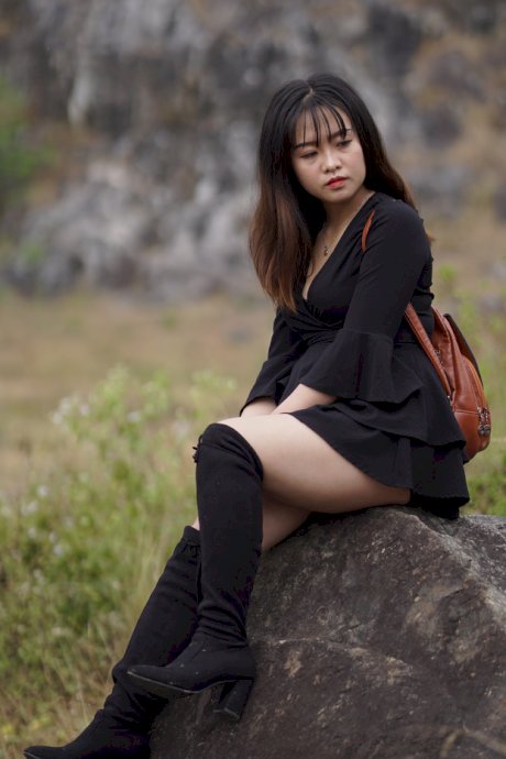 Gorgeous Asian babe posing in her black dress and boots in nature