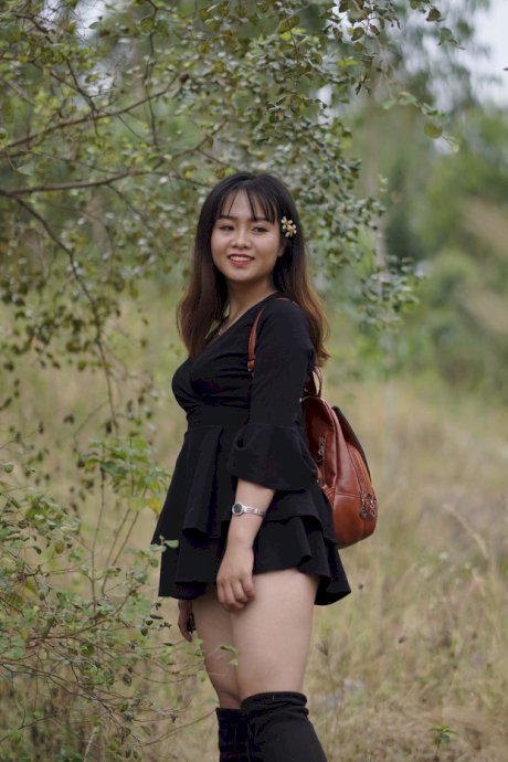 Gorgeous Asian babe posing in her black dress and boots in nature
