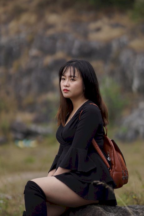 Gorgeous Asian babe posing in her black dress and boots in nature