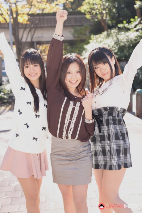 Three Japanese girls in skirts pose outdoors for a SFW shoot