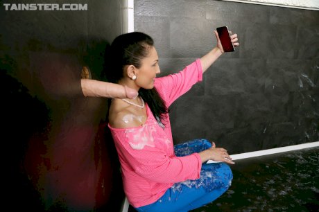 Clothed brunette takes selfie of a cock shooting jizz on her via glory hole