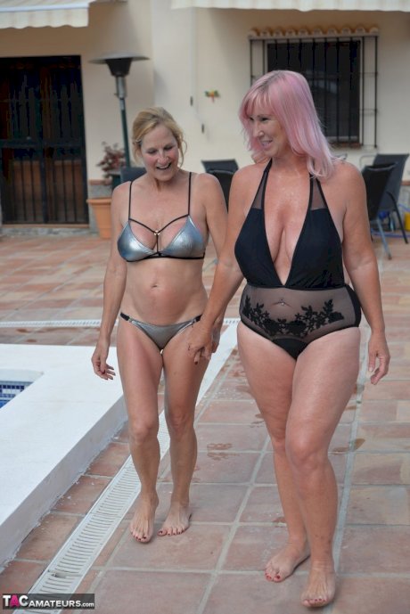 Mature BBW Melody and her girlfriend walk hand in hand by a pool in swimwear