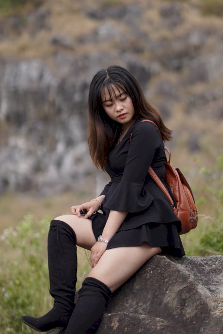 Gorgeous Asian babe posing in her black dress and boots in nature