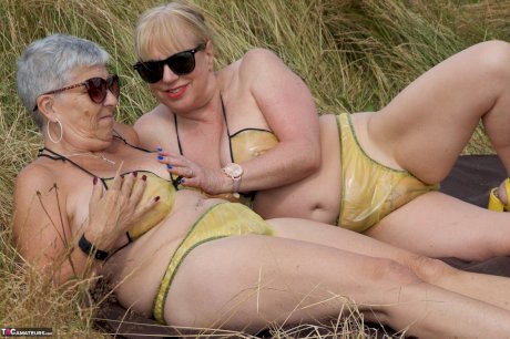Old lesbians catch rays on their large breasts while sunbathing in a field