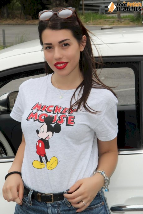Hot girl displays her sexy feet in a car while wearing a Mickey Mouse T-shirt