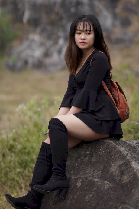 Gorgeous Asian babe posing in her black dress and boots in nature