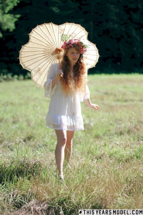 Charming redheaded teen Dolly Little holds a parasol while getting naked - Photo 1