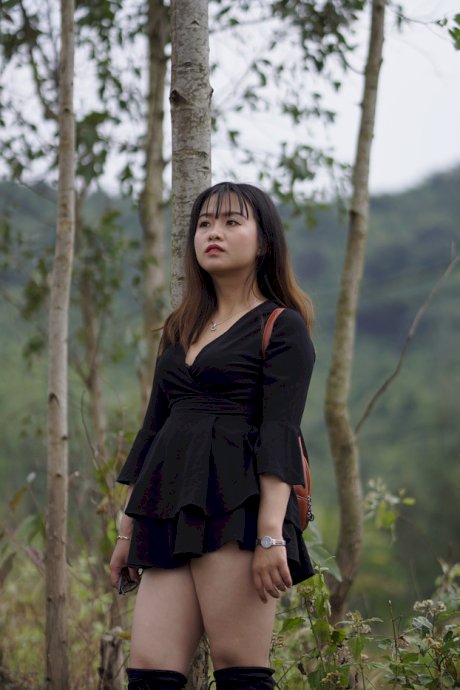 Gorgeous Asian babe posing in her black dress and boots in nature