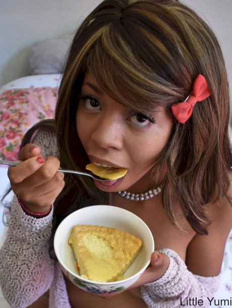 Black babe in gray socks Little Yumi flaunts her tits while eating on a bed