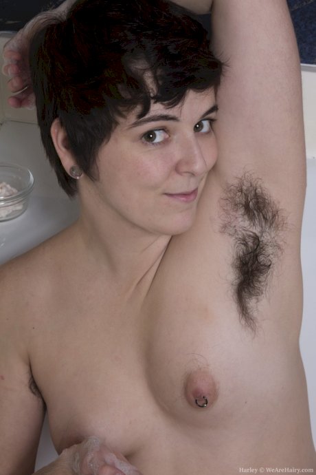 Brunette babe Harley shows her hairy legs and combs her pussy in the bathtub