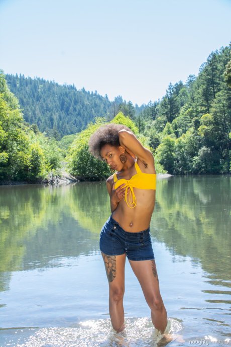 Afro-American babe Nikki Darling exposes her hairy inked body in the river