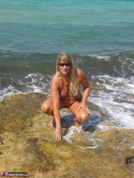 Middle-aged blonde Sweet Susi poses totally nude in a tidal pool
