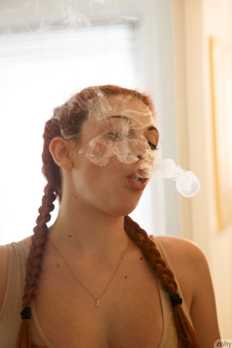 Redhead teen Gina Rosini smokes and shows her big breasts indoors