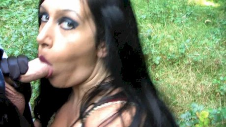 Goth woman Lady Angelina sucks the sperm from a big cock near the woods