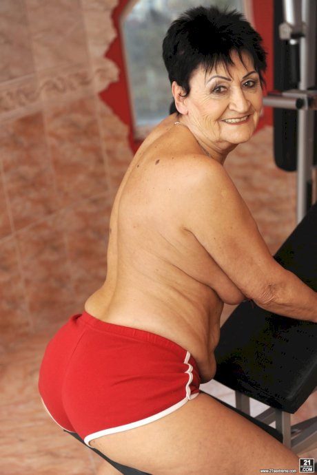 Sassy granny Anastasia strips at the gym to spread naked on the equipment